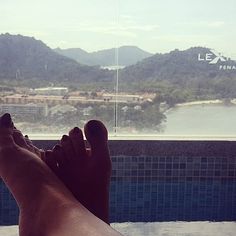 a person's feet are shown in front of a swimming pool and mountain view