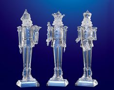 three crystal figurines are standing next to each other on a blue background,