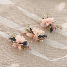 two small pink flowers are tied together with white ribbon on a bed sheet, and one flower has been pinned to the side