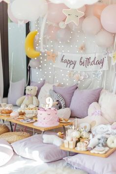 a birthday party with balloons, cake and other items on the table in front of it