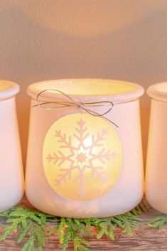 three white candles with snowflakes on them sitting next to each other and tied in twine