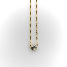 This 14k gold diamond necklace is a classic everyday piece and a great staple for any jewelry collection. The Old European Cut diamond has a lot of sparkle—its facets create excellent light play that pops when worn. The bezel setting is simple and the width of the chain balances the diamond well. This is a vintage piece, circa 1990’s, that contains a much older antique diamond. The perfect combination of old and new.  The natural antique diamond is Old European Cut, VS2 in clarity and I-J in color. It measures 5 mm across and weighs approximately .4 of a carat.   The chain measures 16 1/4”. It is marked 14k, ITALY, and with the maker’s mark “Fancy”. The necklace weighs 2.8 grams. Classic Yellow Gold Solitaire Diamond Necklace, Classic 14k Gold Solitaire Necklace With Single Cut Diamonds, Classic Yellow Gold Solitaire Necklace With Single Cut Diamonds, Classic Yellow Gold Diamond Necklace, Minimalist 14k Gold Diamond Necklace With Bezel Setting, Yellow Gold Diamond Necklace With Single Diamond, Minimalist Diamond White Necklace With Bezel Setting, Minimalist Round Cut Bezel Setting Necklace, Minimalist Bezel Set Necklace For Anniversary