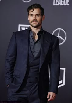 a man in a suit standing on a red carpet