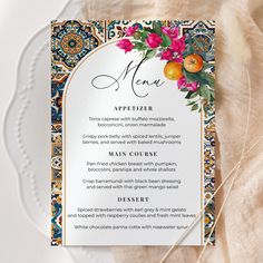 a menu card with an orange and pink flower arrangement on it next to a white plate