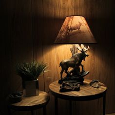 a lamp that is sitting on top of a table next to a small table with a deer figurine