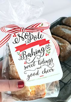 a hand holding a bag of baked goods in front of some pastries on a cooling rack