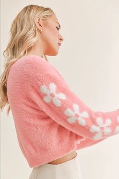 This soft and sweet cropped cardigan in a bold barbie pink features covered buttons and a white floral pattern down the sleeves. Pair this adorable cardigan with a jeans for a more casual look or dress it up for a date night with a white skirt and heels. Trendy Long Sleeve Cropped Sweater For Spring, Feminine Long Sleeve Cardigan For Spring, Spring Soft Knit Cropped Sweater For Loungewear, Spring Soft Knit Cropped Sweater, Chic Pink Cropped Sweater For Winter, Cozy Cropped Sweater For Spring Loungewear, Trendy Spring Cardigan, Trendy Pink Soft Knit Cardigan, Spring Cropped Soft Knit Fitted Sweater