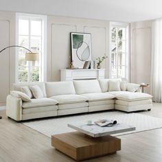 a living room with white furniture and large windows