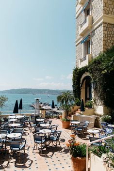 an outdoor dining area with tables and chairs near the water