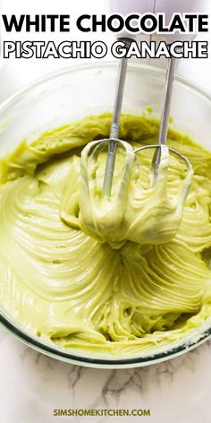 a bowl filled with white chocolate and green icing next to a whisk