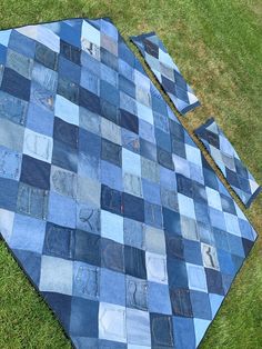 a blue patchwork quilt laying on the grass