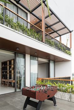 an outdoor game table in front of a balcony with potted plants on the balconies