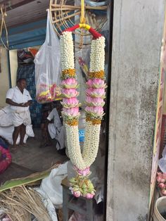 flowers are hanging from the ceiling in front of people sitting on the floor and looking at them