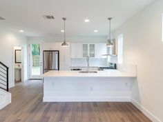 an empty kitchen with white cabinets and wood flooring in the middle of the room