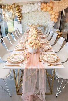 a long table with plates and place settings on it, along with balloons in the background