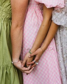 two women in dresses holding hands with one woman's hand on the other side