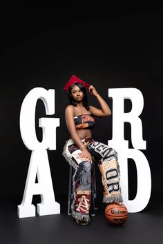 a woman sitting on top of a basketball ball in front of the word grad