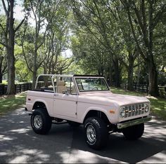 an old pink truck parked in front of some trees