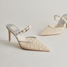 a pair of white high heel shoes with pearls on the toes and heels are sitting next to each other