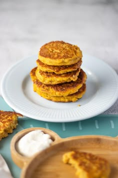 a stack of pancakes sitting on top of a white plate next to a bowl of yogurt