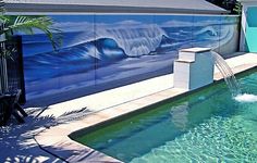 a pool with a mural on the side of it and a fountain in front of it