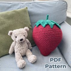 a teddy bear sitting next to a crocheted strawberry pillow on a couch with the text, free pattern