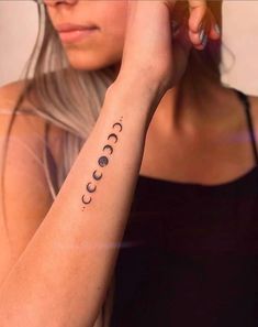 a woman is holding her arm up with the moon and phases tattooed on it