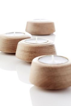 three wooden candles sitting next to each other on top of a white surface with one candle lit