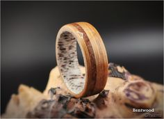 a wooden ring with antler wood inlays on it sitting on top of a rock