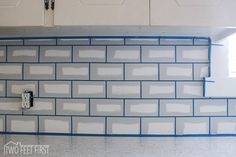 a kitchen with white cabinets and blue lines on the backsplash