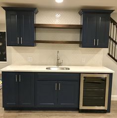 a kitchen with dark blue cabinets and white counter tops, stainless steel dishwasher