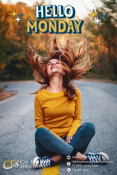 a woman is sitting on the road with her hair in the air, and smiling