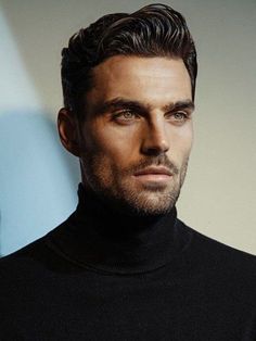 a close up of a person wearing a black turtle neck sweater and looking at the camera