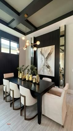 a dining room table with white chairs and a painting hanging on the wall above it