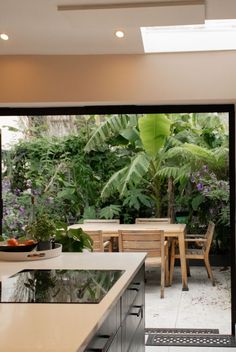 an open kitchen and dining area with plants in the background