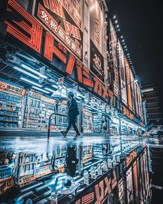 a man walking down a street next to tall buildings with neon signs on the side