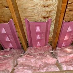 some pink candles sitting on top of boxes in front of wooden walls and flooring