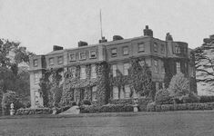 an old black and white photo of a large building with ivy growing on it's sides