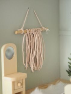 there is a small doll house with a bed and table in the room, it has a macrame dream catcher hanging on the wall