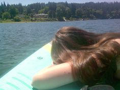 a woman laying on top of a surfboard in the water