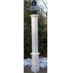 a white post with a light on top in the snow