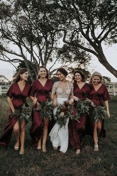 the bride and her bridesmaids are all dressed in burgundy dresses with greenery