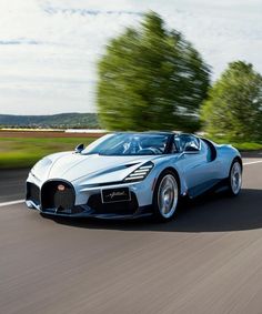 a bugatti is driving down the road in front of some trees and grass