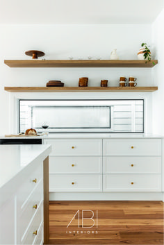 a kitchen with white cabinets and wooden shelves