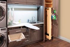 a washer and dryer in a room with wood flooring, built - in shelving