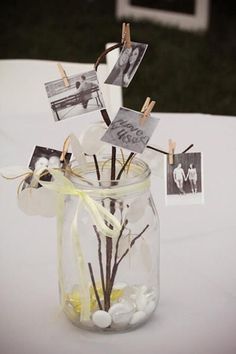 a glass jar filled with pictures and cards on top of a white table cloth covered table