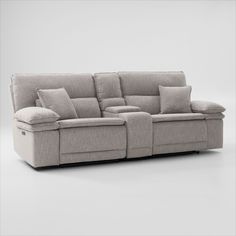 a grey couch with pillows on it and two recliners in front of it