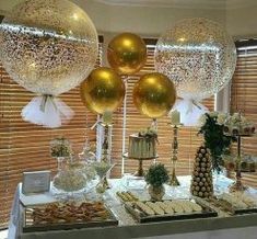 a table topped with lots of balloons filled with gold and white confetti balls