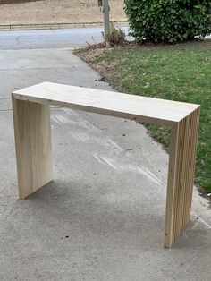 a wooden bench sitting on the side of a road next to a grass covered field