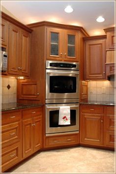 a kitchen with wooden cabinets and stainless steel ovens in the center, along with granite counter tops